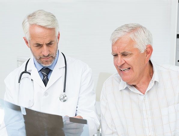 Male doctor explaining x-ray report to senior patient in the medical office